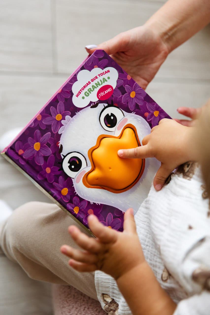 Manos de un peque tocando el pico de goma del pato en el libro Granja de Alimax
